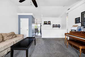 Living room with carpet flooring, ceiling fan with notable chandelier, and lofted ceiling