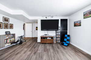 Living room featuring baseboards, rail lighting, and wood finished floors