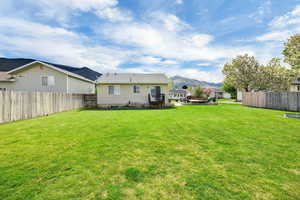 Rear view of house featuring a yard, fence, and a mountain view