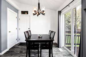 Dining space featuring an inviting chandelier, vaulted ceiling, and wood finished floors