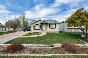 View of front of property with fence, driveway, and a front lawn