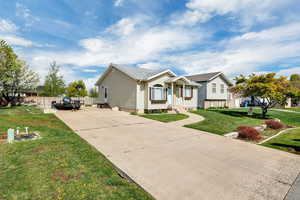 Ranch-style home with concrete driveway, fence, and a front yard