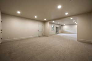 Spare room with baseboards, recessed lighting, and light colored carpet