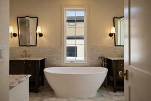 Full bathroom featuring tile walls, wainscoting, a sink, and marble finish floor