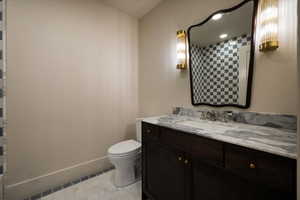 Bathroom with baseboards, toilet, and vanity