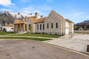 View of front facade featuring driveway, a chimney, fence, a mountain view, and stone siding