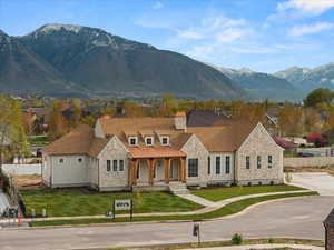 View of front of home featuring a porch, fence, a mountain view, and stone siding
