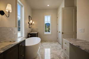 Full bath with vanity, marble finish floor, recessed lighting, backsplash, and a soaking tub