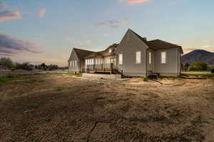 Back of house at dusk with central air condition unit and a wooden deck