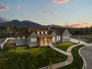 View of front of house featuring a chimney, fence, a mountain view, a yard, and stone siding