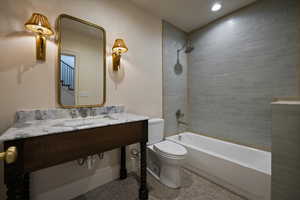Bathroom featuring washtub / shower combination, tile patterned flooring, vanity, and toilet
