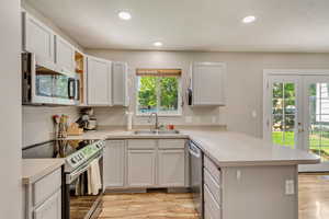 Kitchen featuring french doors, appliances with stainless steel finishes, a sink, a peninsula, and light wood-style flooring