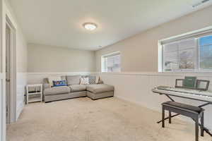 Living area featuring visible vents, carpet, and a wainscoted wall