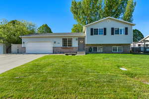 Tri-level home featuring a front yard, brick siding, concrete driveway, an attached garage, and central air condition unit