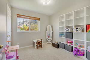 Recreation room with carpet floors, a textured ceiling, and baseboards
