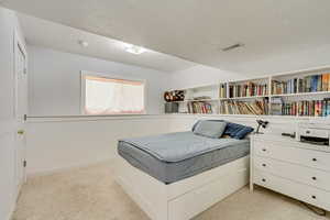 Bedroom featuring a textured ceiling, light colored carpet, and visible vents