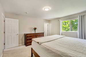 Bedroom featuring baseboards, a textured ceiling, and light colored carpet