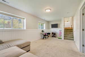 Living area featuring visible vents, wainscoting, carpet floors, and stairs
