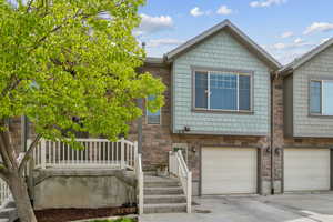 View of front of home with an attached garage, driveway, and stone siding