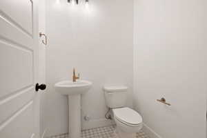 Half bathroom featuring baseboards, tile patterned flooring, and toilet