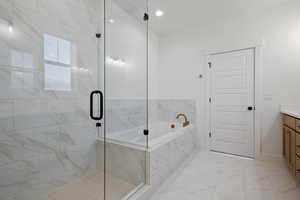 Full bath with vanity, marble finish floor, baseboards, a shower stall, and a garden tub