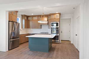 Kitchen featuring a center island, light countertops, appliances with stainless steel finishes, and wood finished floors