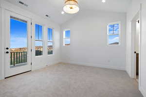 Unfurnished room featuring carpet, lofted ceiling, and visible vents
