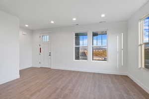 Interior space with baseboards, visible vents, plenty of natural light, and wood finished floors