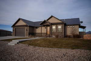 Craftsman-style home with a standing seam roof, driveway, and metal roof
