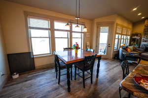 Dining room featuring vaulted ceiling, dark wood finished floors, and a fireplace