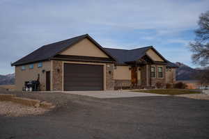View of front of home featuring a standing seam roof, metal roof, concrete driveway, an attached garage, and stone siding