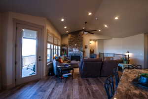 Living room featuring ceiling fan, a fireplace, vaulted ceiling, wood finished floors, and recessed lighting