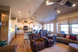 Living area with a ceiling fan, vaulted ceiling, recessed lighting, and light wood-style flooring