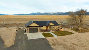 View of front of property featuring driveway, metal roof, a mountain view, a rural view, and an attached garage