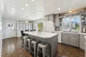 Kitchen with a kitchen island, open shelves, a sink, gray cabinetry, and white appliances