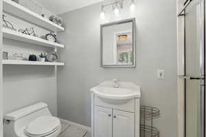 Bathroom featuring vanity, baseboards, tile patterned flooring, and toilet