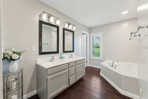 Full bathroom featuring a sink, baseboards, a bath, and hardwood / wood-style floors