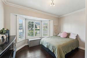 Bedroom with a textured ceiling, baseboards, dark wood-type flooring, visible vents, and ornamental molding
