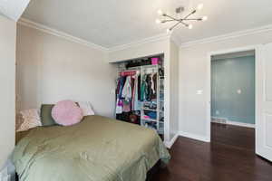 Bedroom with visible vents, wood-type flooring, a closet, baseboards, and a notable chandelier