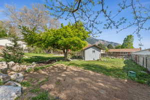 View of yard with a mountain view, an outbuilding, a fenced backyard, and a storage unit