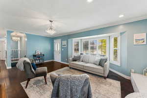 Living room featuring an inviting chandelier, recessed lighting, baseboards, and dark wood-style flooring