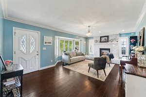 Living area featuring an inviting chandelier, crown molding, hardwood / wood-style floors, baseboards, and a textured ceiling