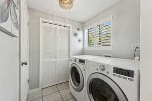 Laundry area featuring laundry area, baseboards, light tile patterned floors, and washer and dryer