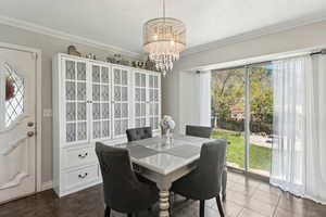 Tiled dining space with crown molding and a chandelier