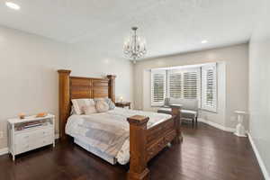 Bedroom with baseboards, recessed lighting, dark wood finished floors, and a notable chandelier