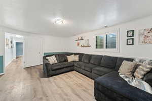 Living area featuring light wood-style floors, ornamental molding, and visible vents
