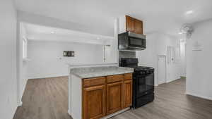 Kitchen featuring recessed lighting, light wood finished floors, black range with gas stovetop, and baseboards