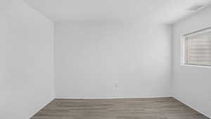 Empty room featuring wood finished floors and visible vents