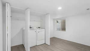 Clothes washing area with washing machine and clothes dryer, laundry area, and light wood-style floors