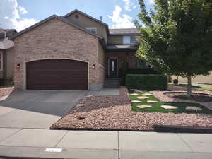 View of front of house featuring driveway, brick siding, and a garage